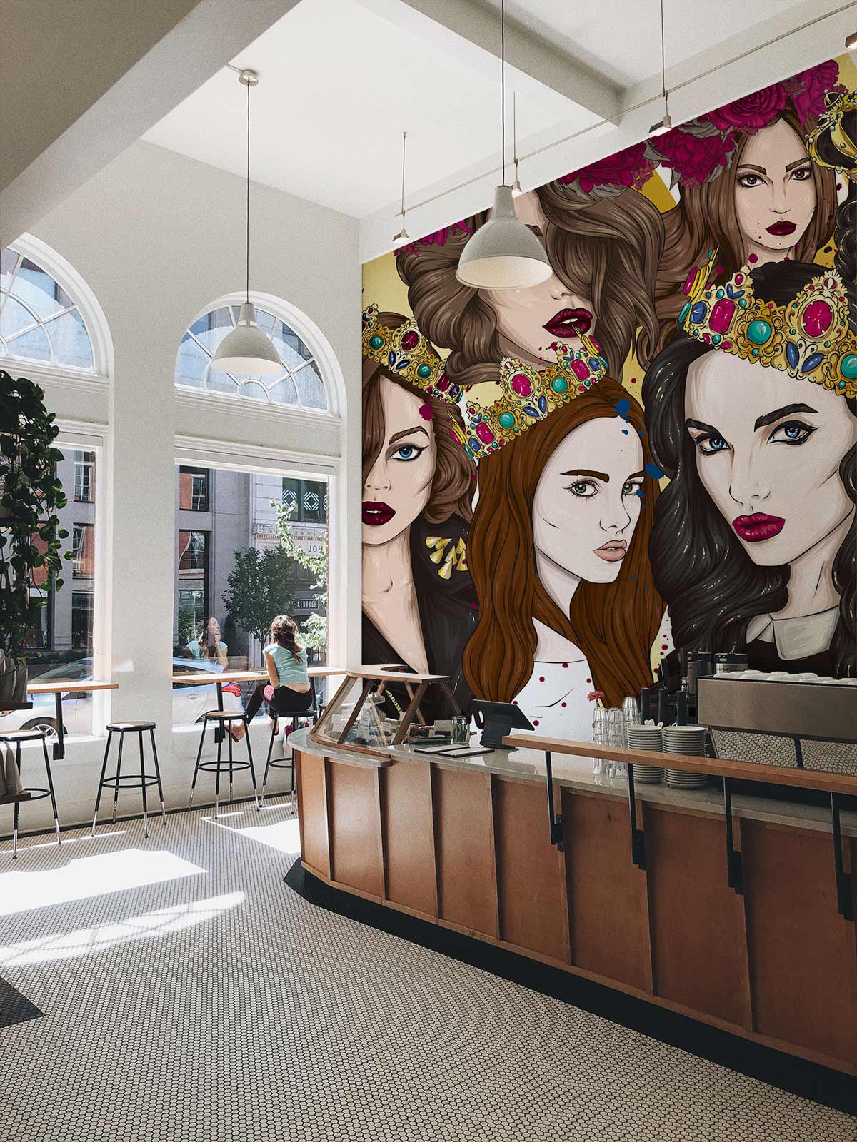 Vibrant Art Deco mural wallpaper in bold jewel tones, café setting with modern wooden counter.