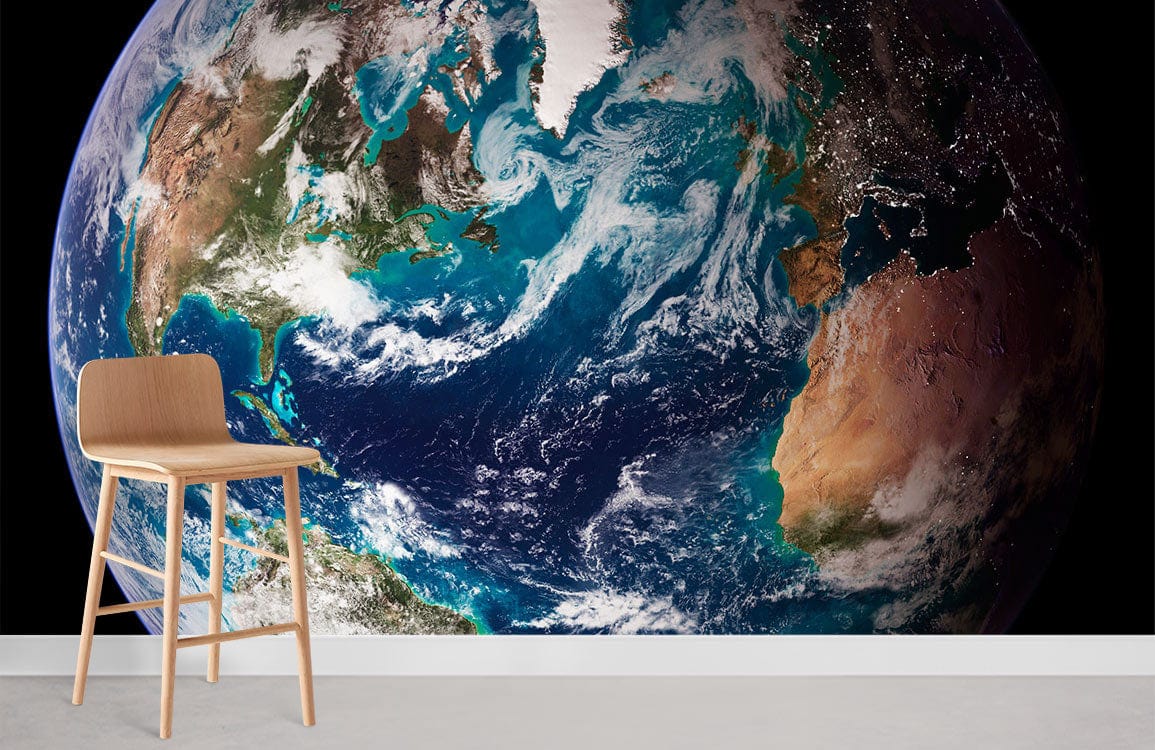 Stunning Earth mural wallpaper with vibrant blue-green planet and light wood chair, white skirting board.