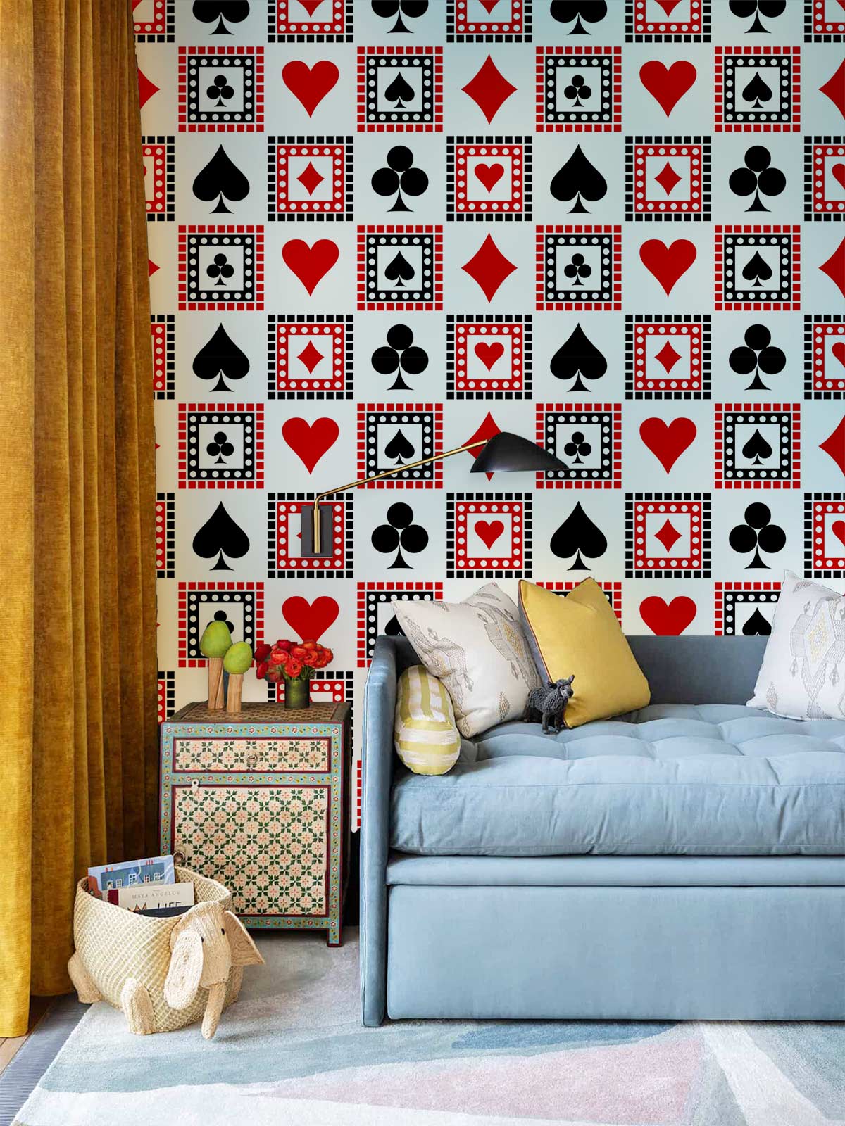 Poker-themed retro wallpaper, vintage side table, mustard curtains, and blue sofa in colourful living room.