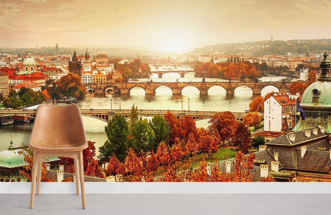 Autumn mural wallpaper with Prague bridges, warm tones, elegant chair, grey flooring, scenic room view.