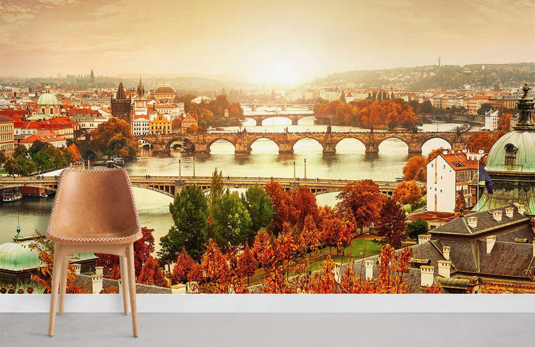 Autumn mural wallpaper with Prague bridges, warm tones, elegant chair, grey flooring, scenic room view.