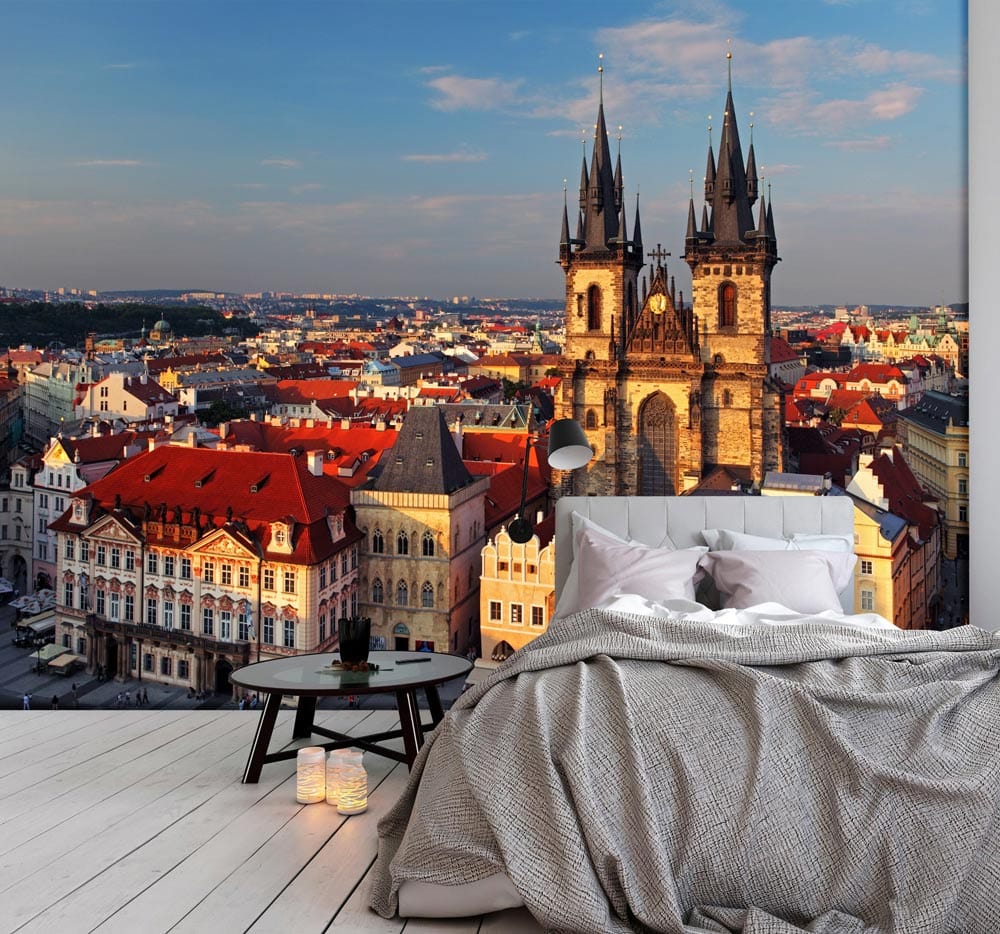 Charming Prague skyline mural wallpaper in bedroom with grey bedding, round table, and wood flooring.