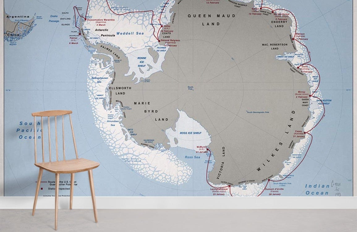 Vintage Antarctic Map Mural Wallpaper in soft earth tones, blue; minimalist chair, light grey flooring.