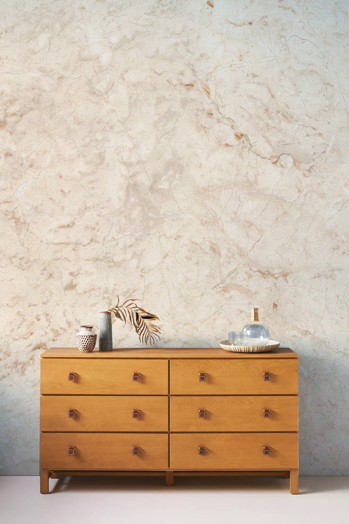 Marble-effect beige textured wallpaper behind wooden dresser, ideal for creating timeless, elegant interiors.