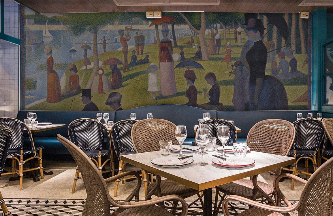Elegant Pointillism mural wallpaper in dining area, featuring rattan chairs and geometric-patterned floor.
