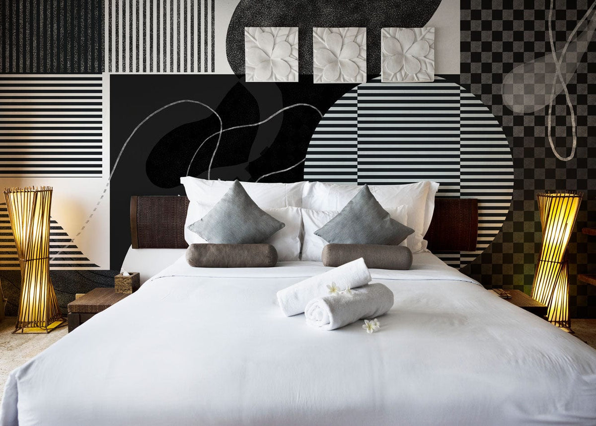 Monochrome geometric wallpaper, contemporary bedroom, white bed, grey cushions, elegant lamps, abstract wall art.