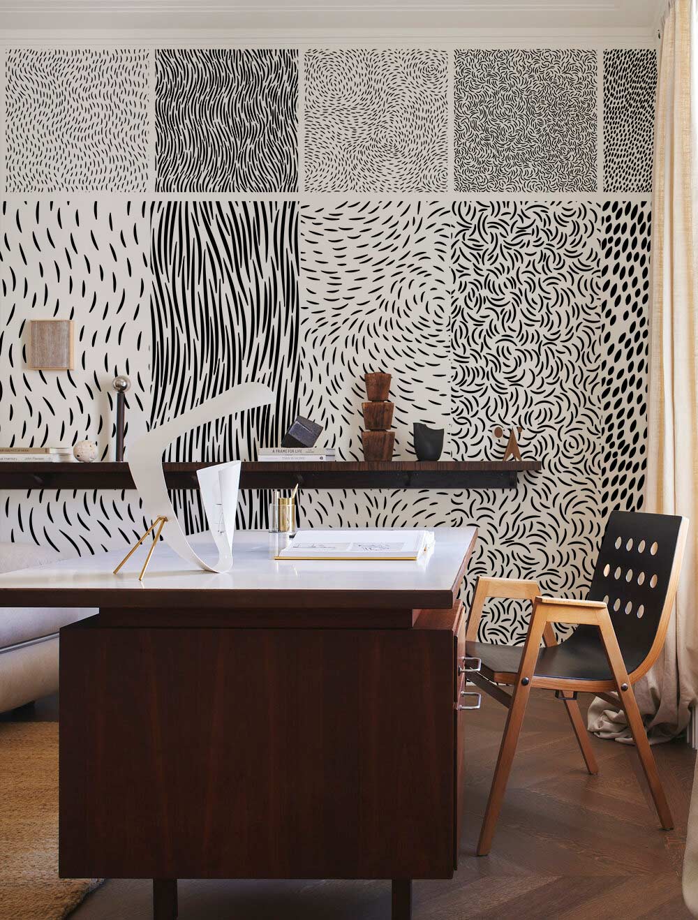 Monochrome abstract wallpaper in modern office, featuring wooden desk, chair, and artistic wall patterns.