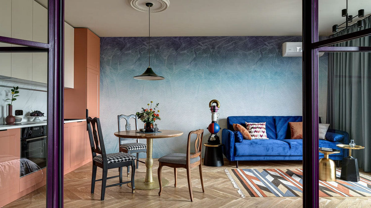 Elegant blue ombre mural wallpaper, modern living room, velvet sofa, wooden flooring, geometric rug.