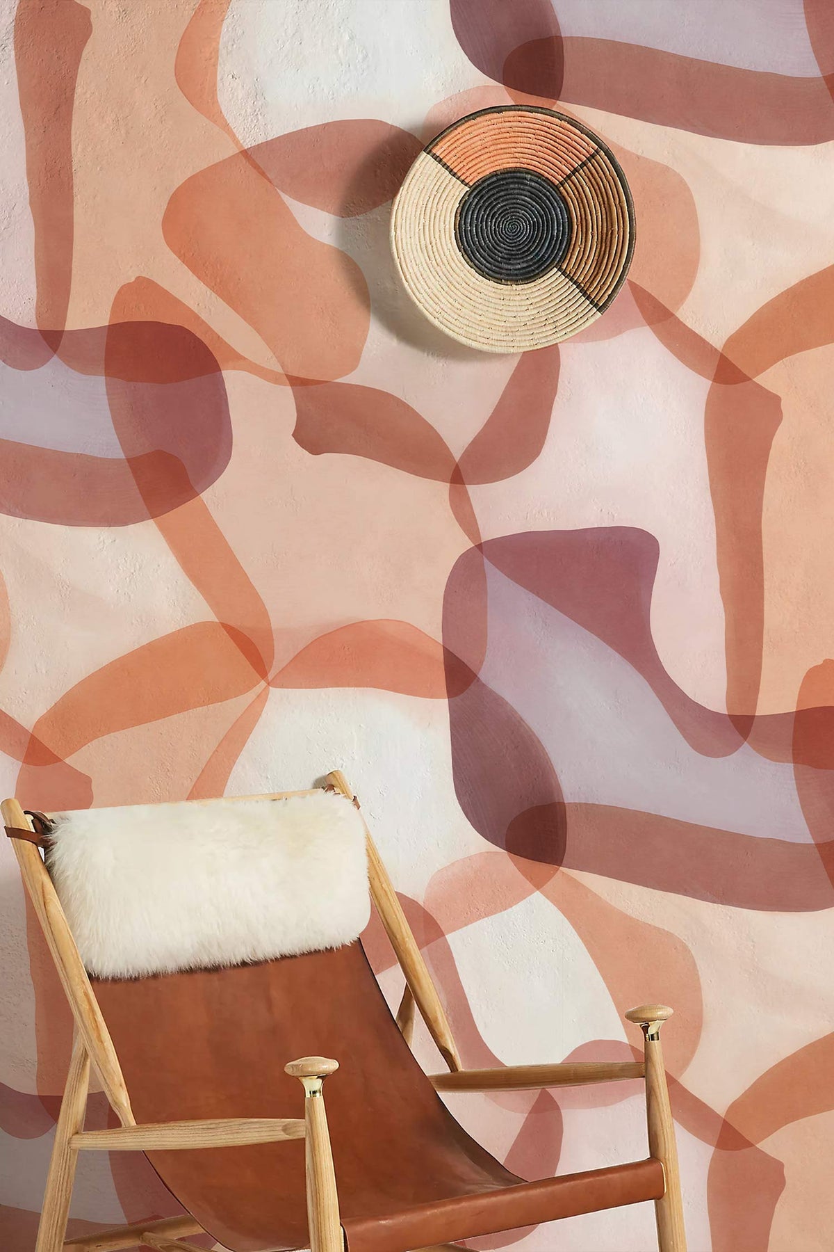 Abstract terracotta and cream geometric wall cover; wooden chair with cream cushion; woven wall art.