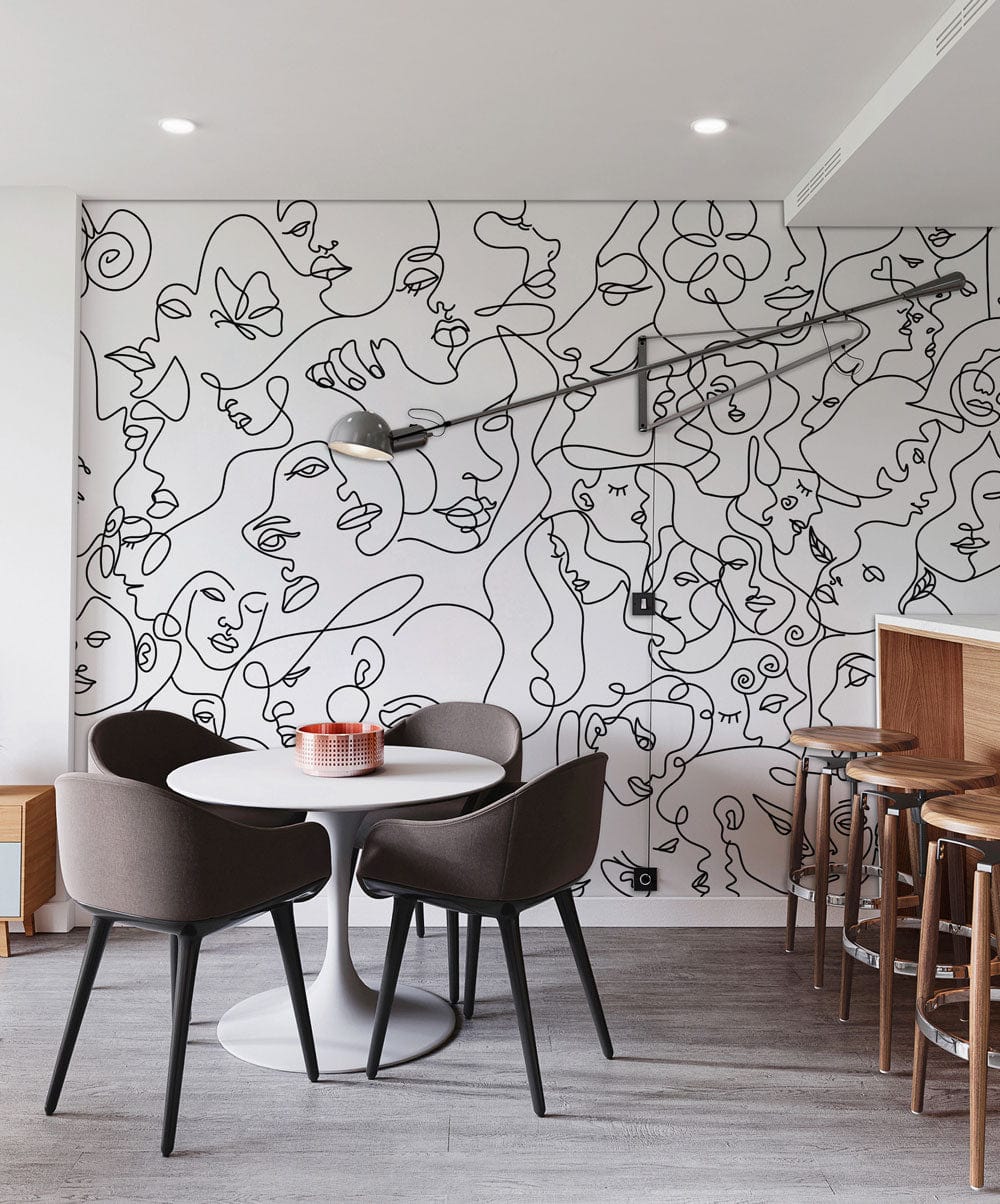 Contemporary dining area with abstract faces wall mural, grey chairs, white table, and wooden stools.