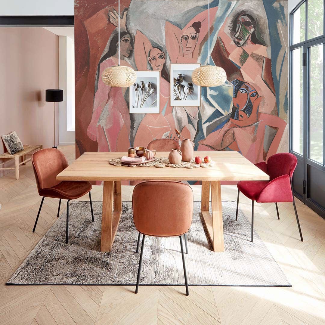 Cubist-style mural wallpaper with earth tones in dining room; wooden table, red chairs, art decor.