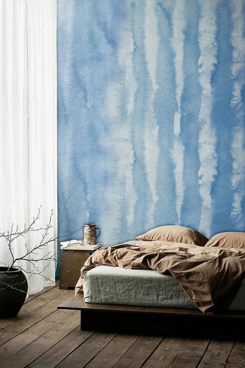 Watercolour Ocean Ripple Effect Blue Wall Mural with wooden flooring in a cosy bedroom setting.