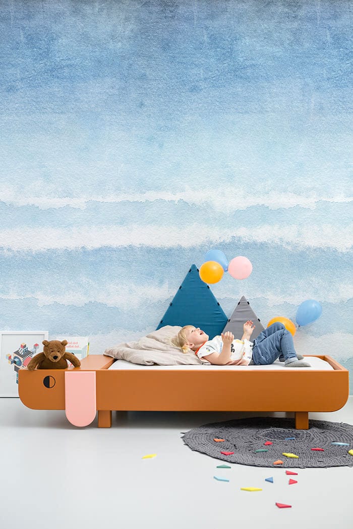 Tranquil Blue Ombre Wall Mural in children's room, wooden bed, colourful balloons, grey rug.