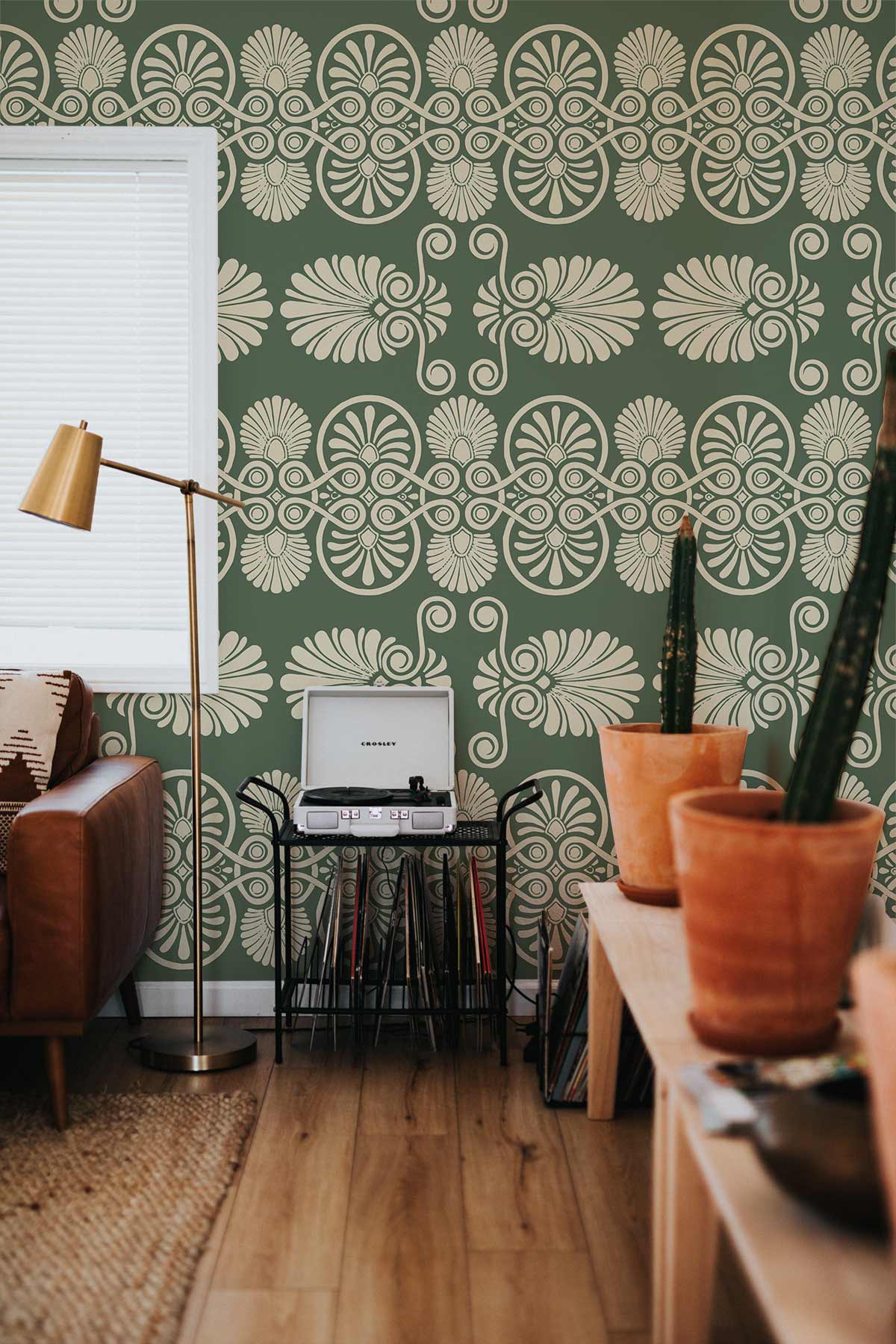 Elegant olive green floral wallpaper in living room with brown sofa, wooden floor, and gold lamp.