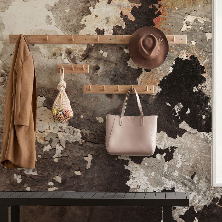Vintage grunge abstract wallpaper in earthy shades; coat rack with hat, bag, and coat.