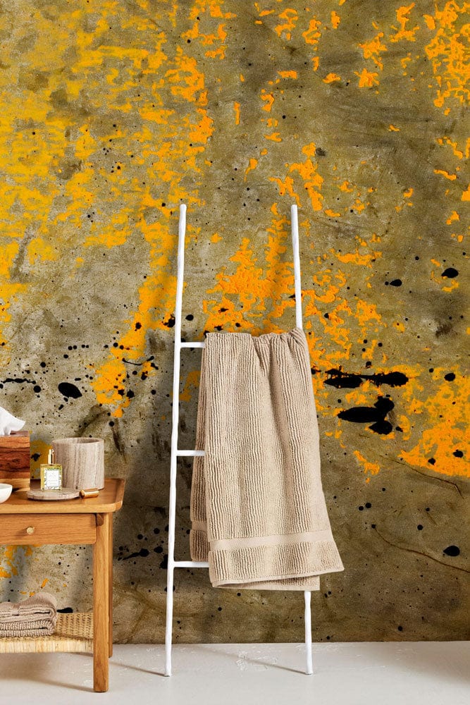 Industrial urban grunge mural wallpaper with ladder and towels, rustic wood table, light floor.