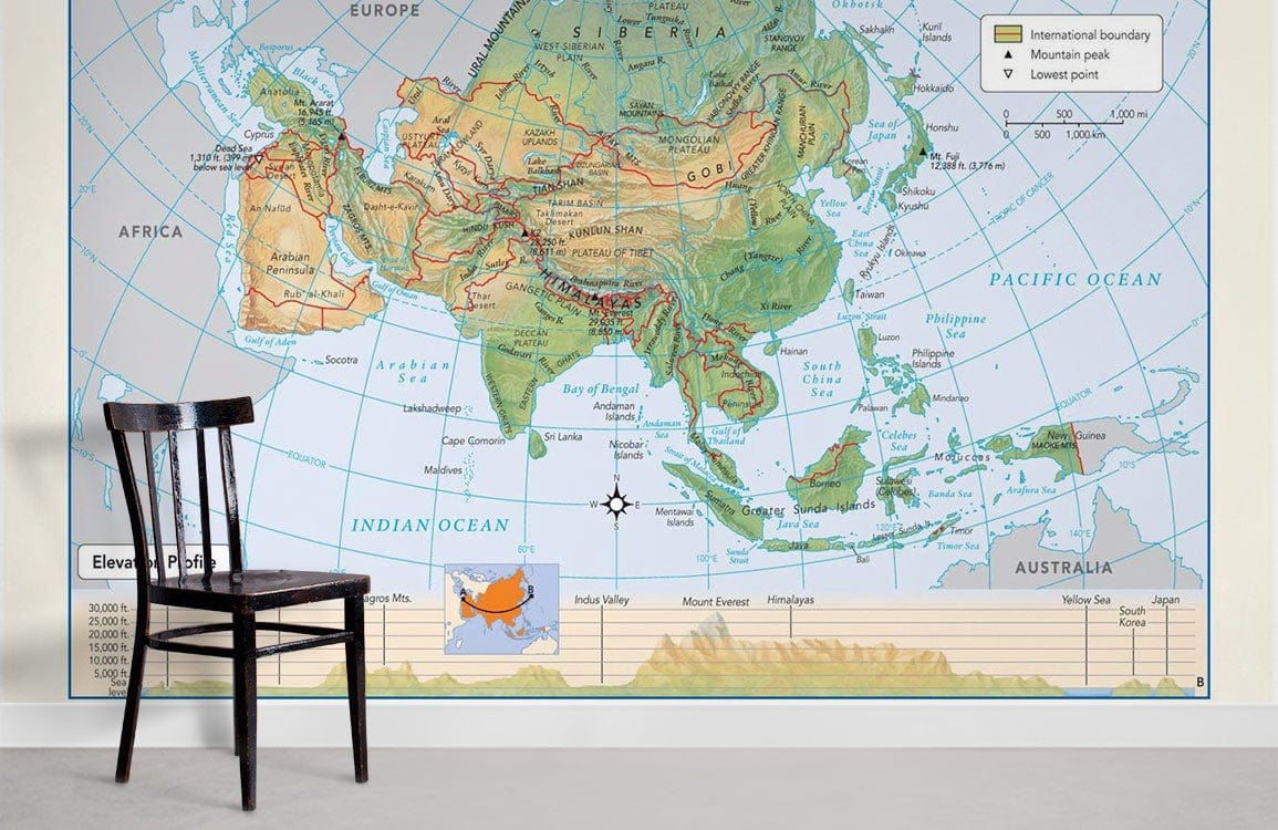 Vintage Asia Pacific map mural wallpaper in earthy tones, minimalist study with wooden chair and flooring.