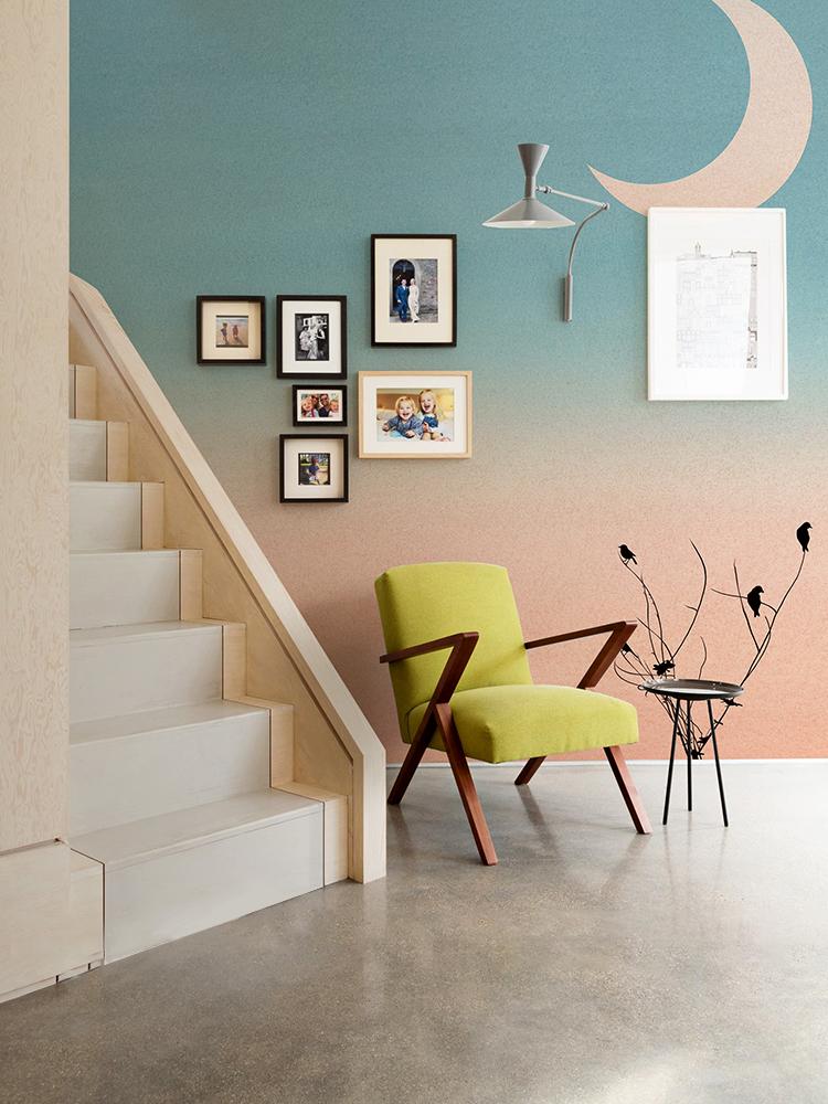 Serene Pastel Sunset Wallpaper with birds, mid-century chair, gallery wall, polished concrete floor, stairway.