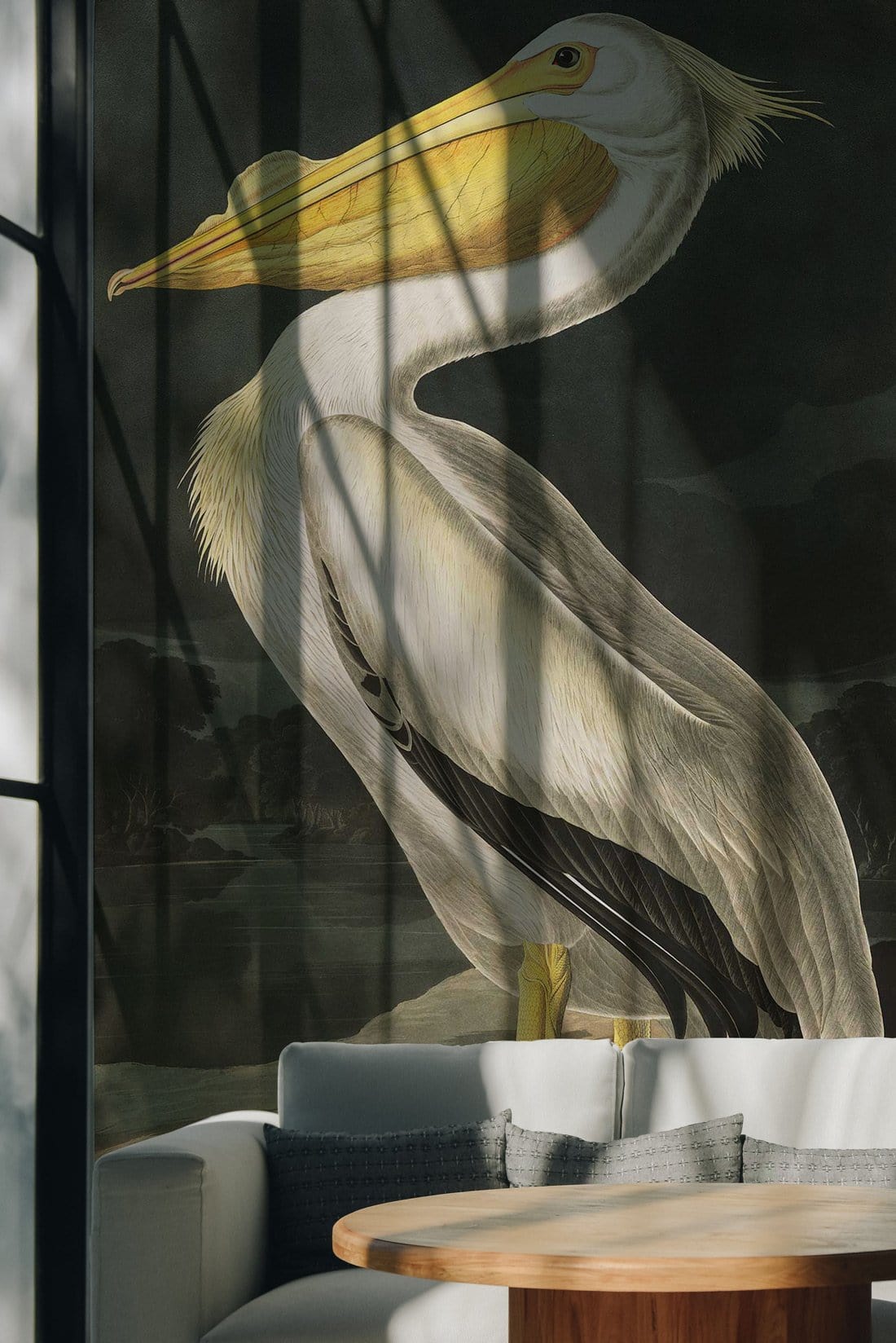 Elegant Vintage Pelican Mural Wallpaper in living room with grey sofa, wooden table, and wildlife art design.