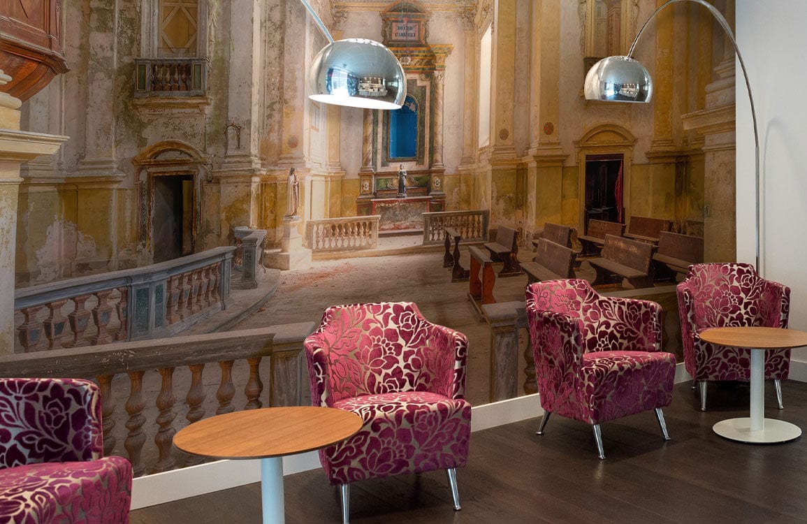 Vintage European Abbey mural in warm earth tones, with ornate chairs, modern lighting, wooden flooring.