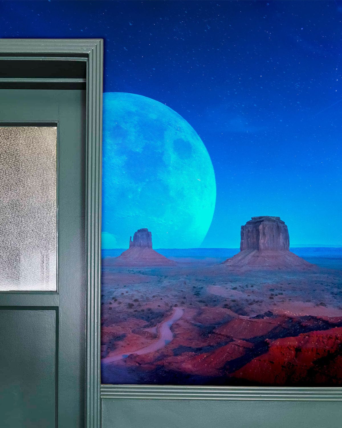 Surreal desert landscape mural in cosmic blue tones, green panelled wall, interior decor.