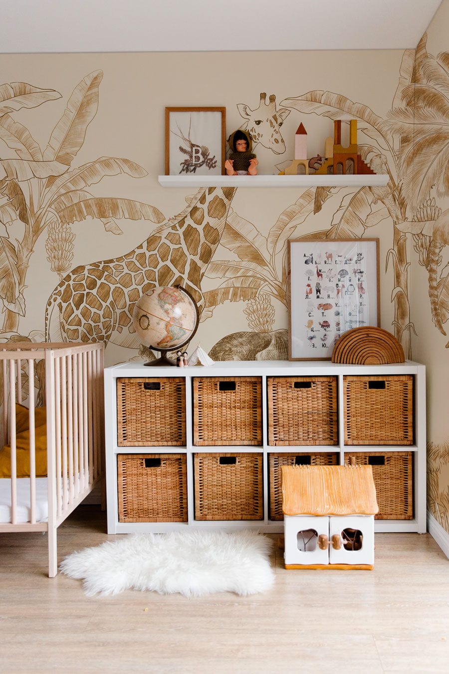 Nursery with Safari Jungle Beige Sepia Wildlife Mural, wicker storage, white cot, light flooring.