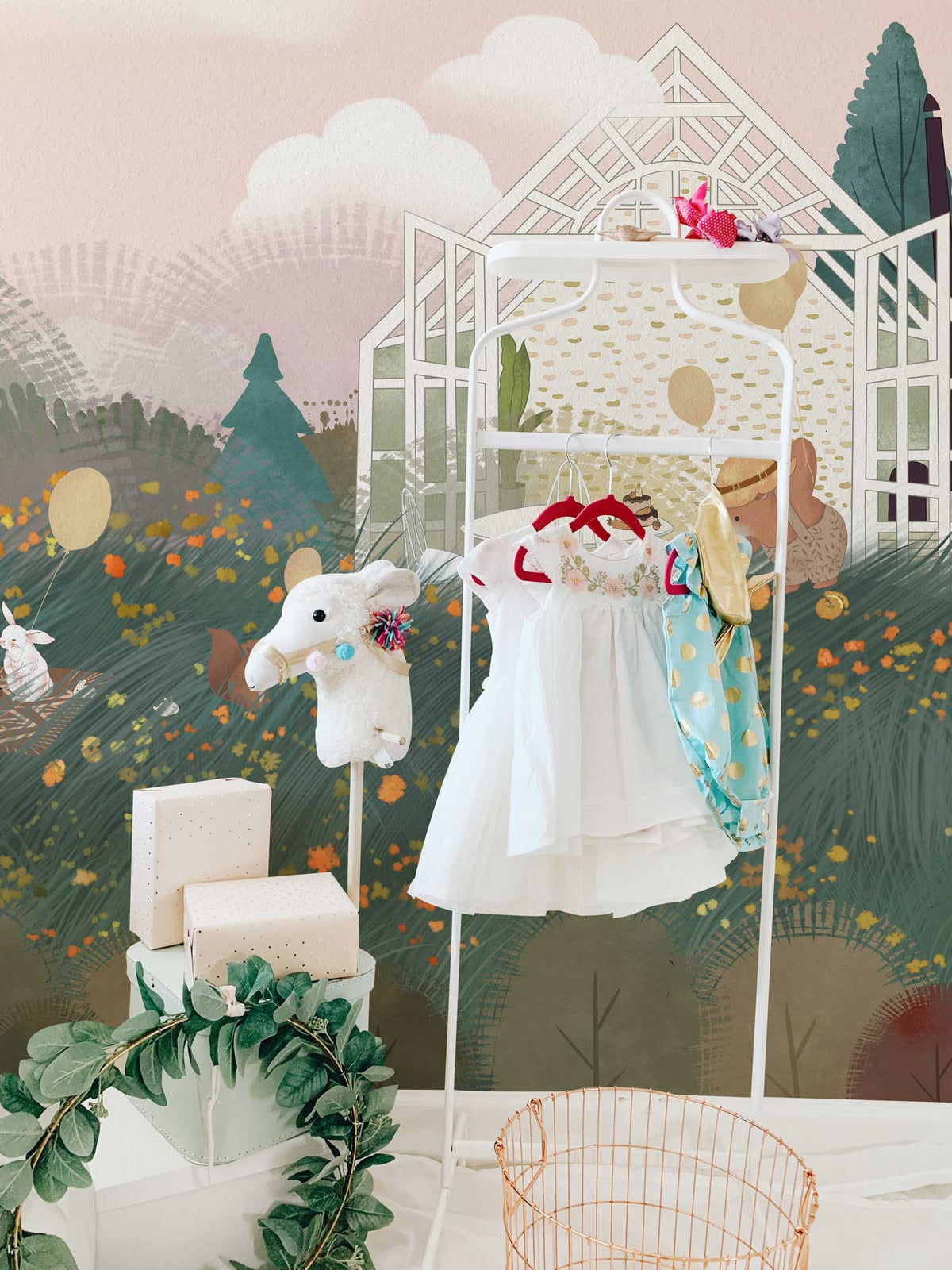 Enchanted Woodland Picnic mural wallpaper in soft pastels with playful clothing rack, nursery setting.