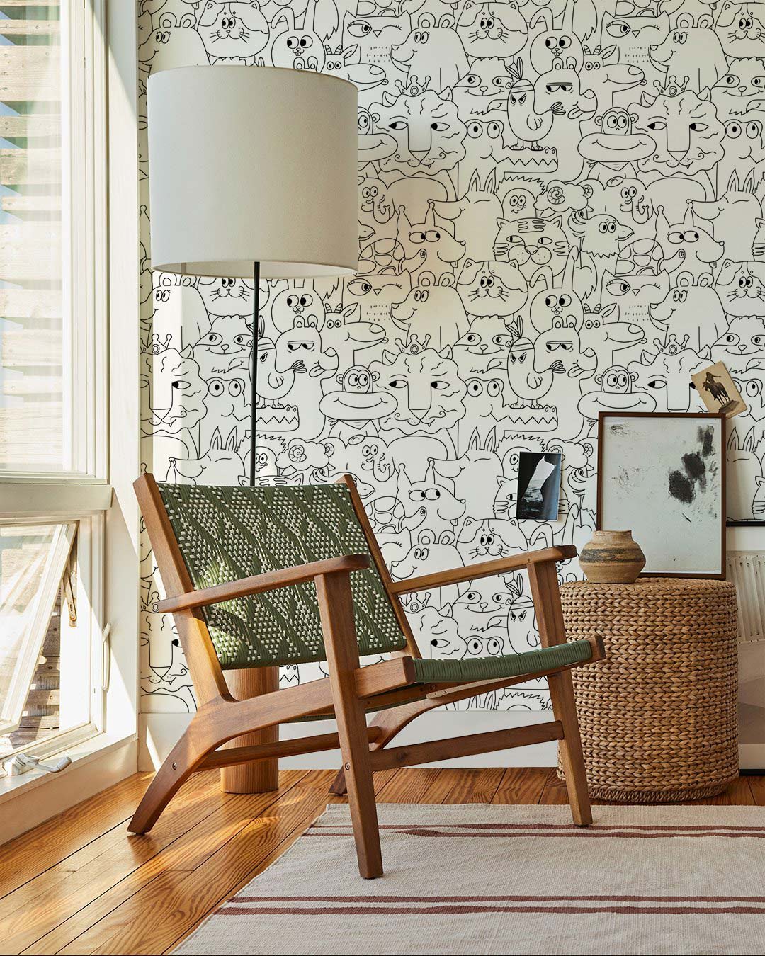 Wooden chair, green-peppered design, beside modern lamp, against playful monochrome doodle animal wallpaper.