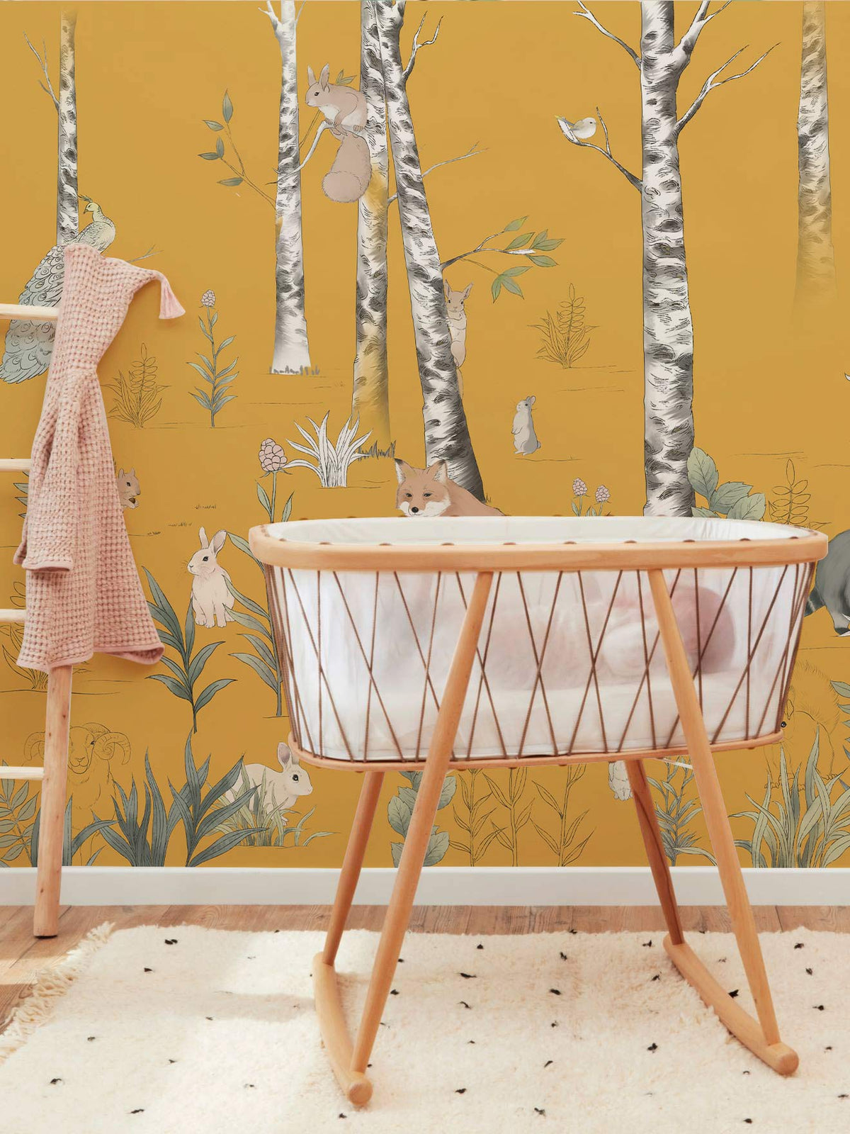 Golden Forest Friends woodland animals mural in nursery with wooden bassinet, yellow walls, soft rug.
