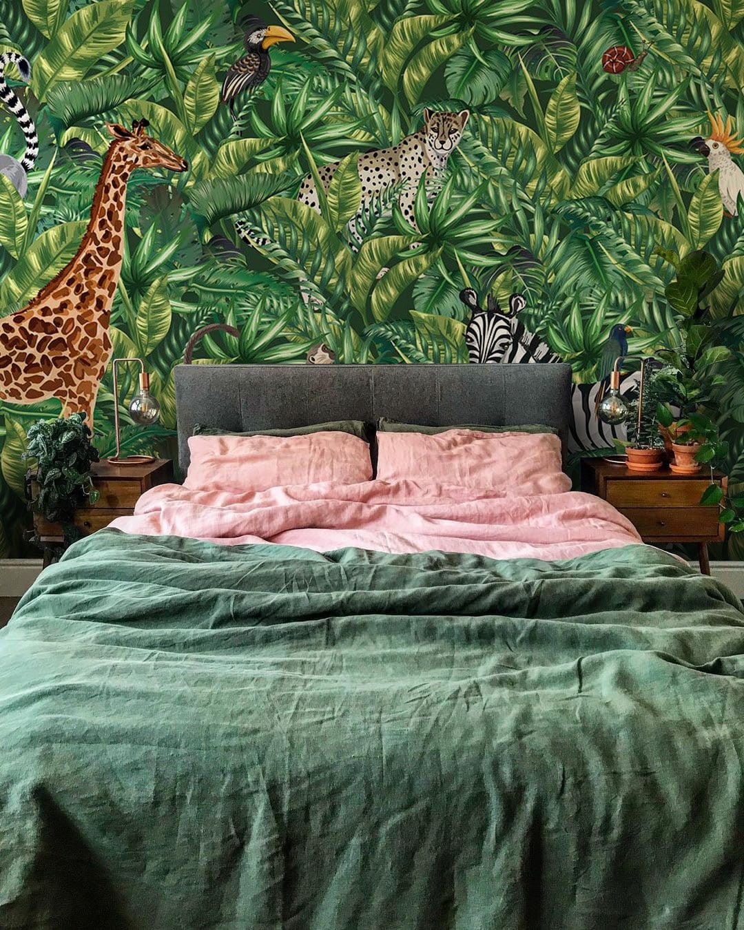 Tropical jungle safari animals mural wallpaper with grey bed, pink bedding, green duvet in bedroom.