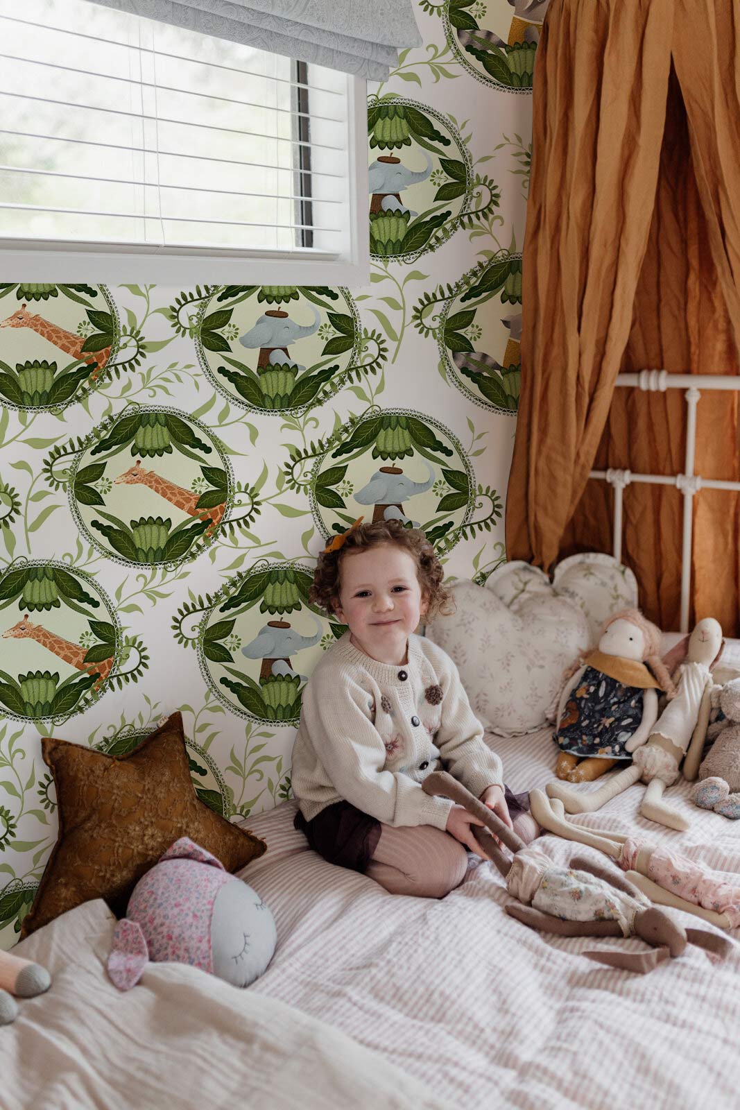 Vintage woodland animal green wallpaper in child's bedroom, complementing white bed and plush toys.