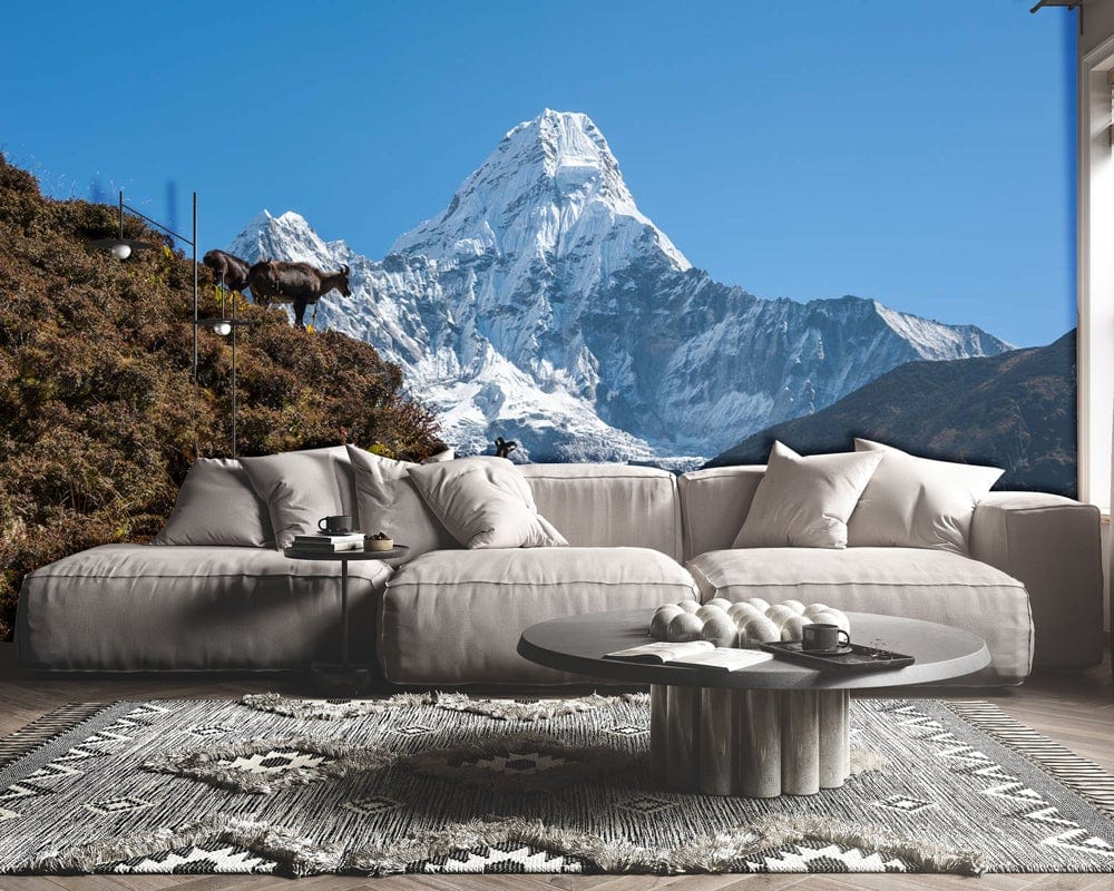 Alt text: Stunning Himalayan mural with goats, grey sectional sofa, round coffee table, modern living room decor.