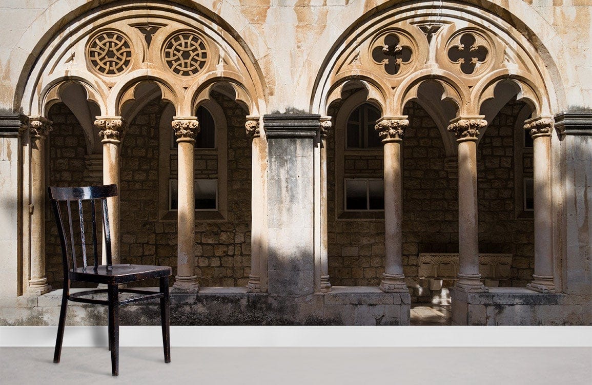 Medieval beige stone mural wallpaper with arches, wooden chair, neutral flooring, elegant architectural design.