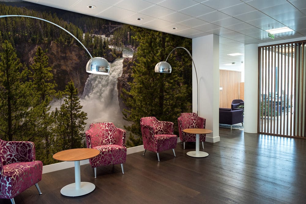 Majestic Forest Waterfall wallpaper in lobby with pink chairs, wooden flooring, and modern lighting.