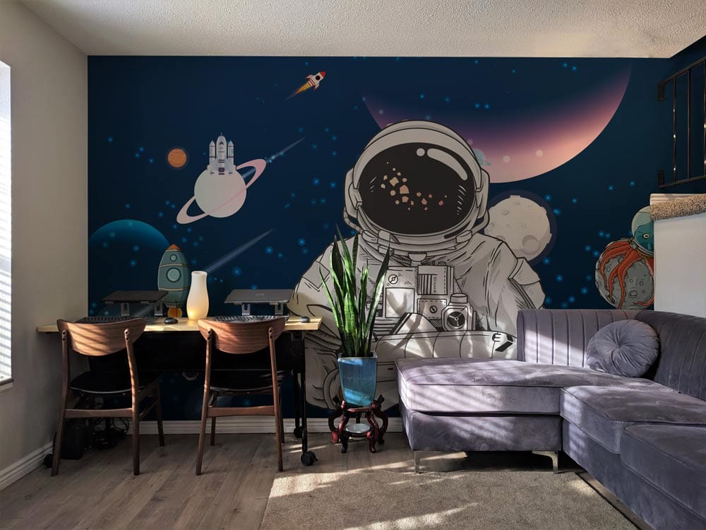 Navy space mural wallpaper with astronauts, rockets; grey sectional sofa; wooden flooring; modern living room.