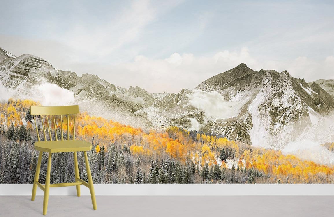 Mountain landscape mural with autumn colours, snowy peaks, grey flooring, and olive chair in living room.