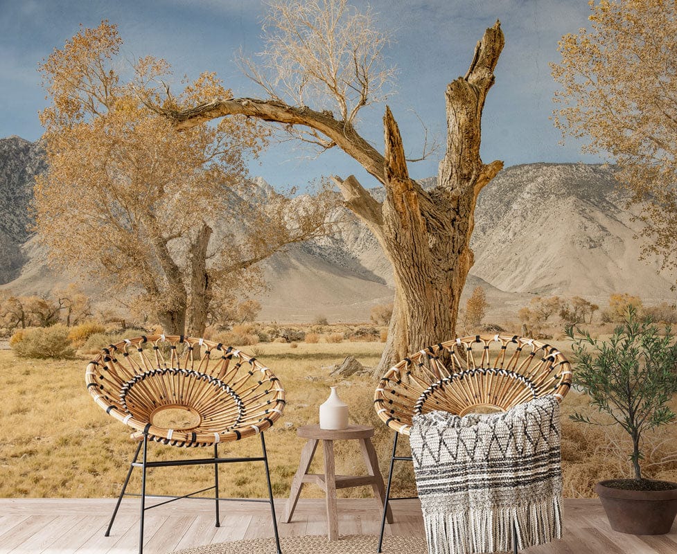 Serene desert landscape wallpaper mural with rustic chairs, woven blanket, and wooden flooring in living room.