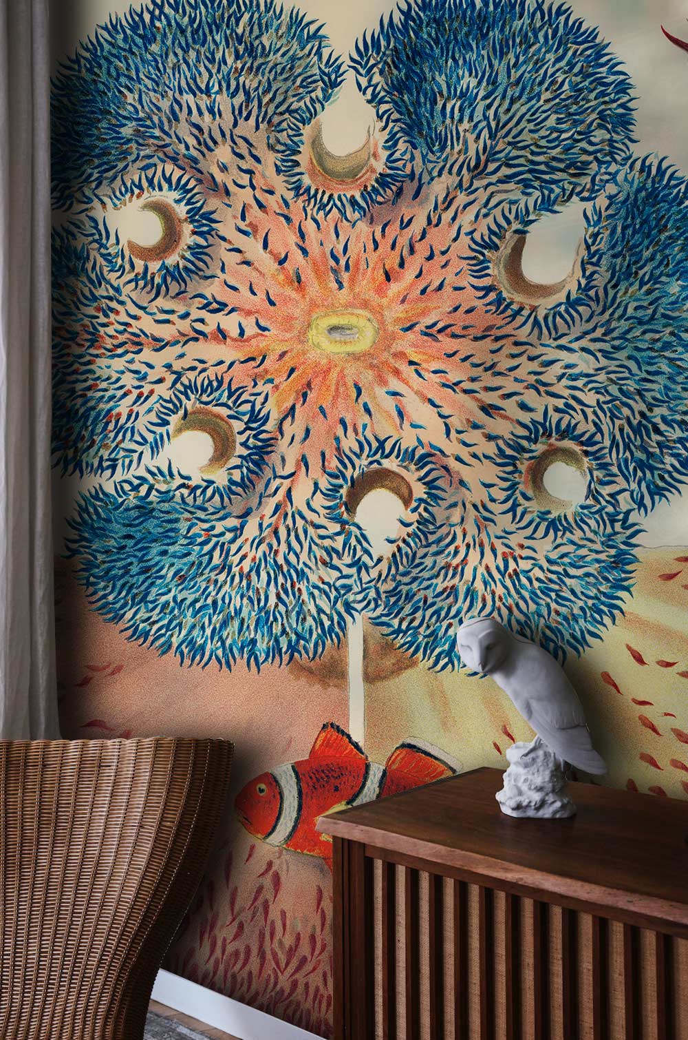 Vibrant coral reef mural wallpaper with clownfish, wooden sideboard, rattan chair, elegant curtain backdrop.