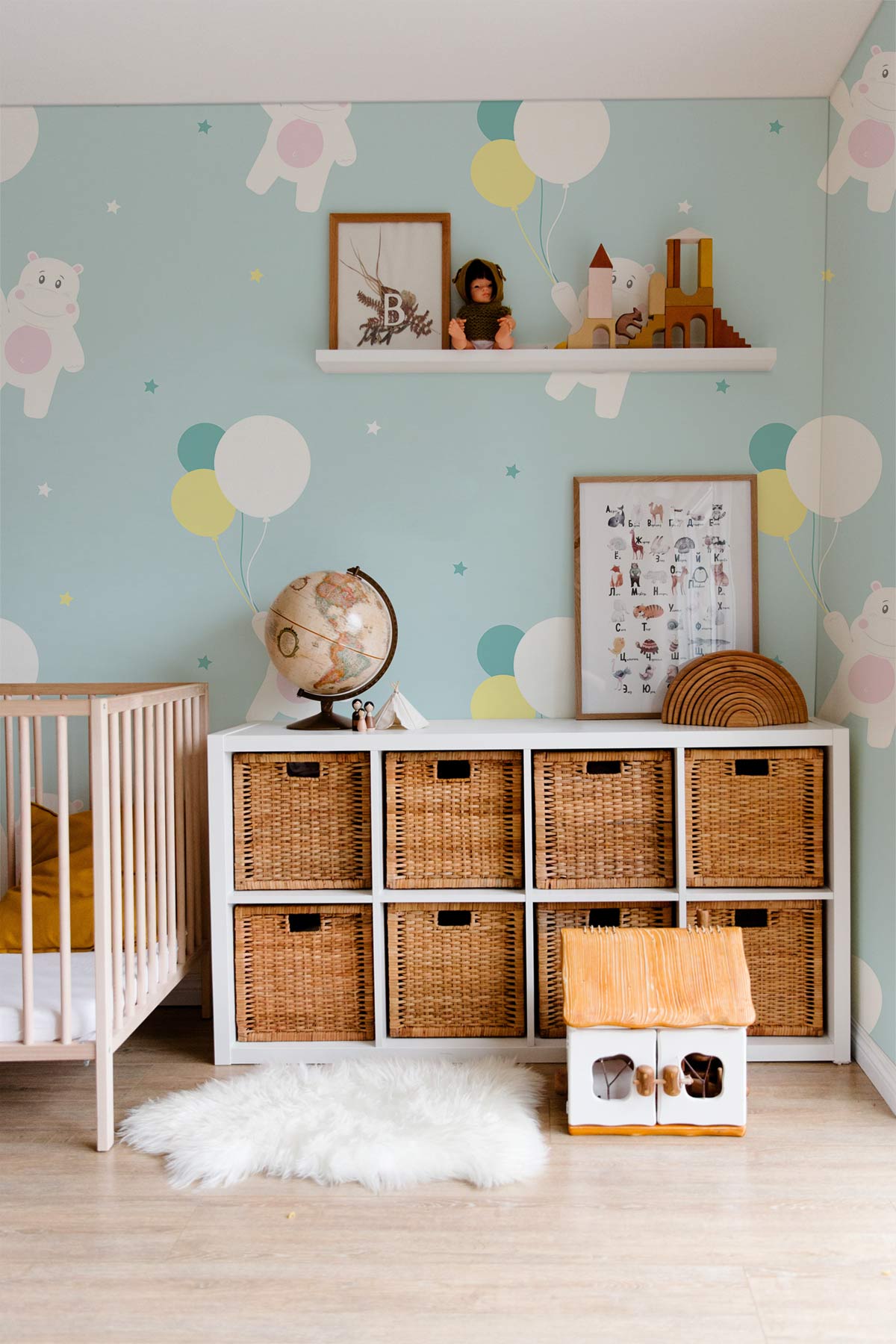 Kids' room with Whimsical Pastel Bears wallpaper, storage unit, light wood flooring, and cot.