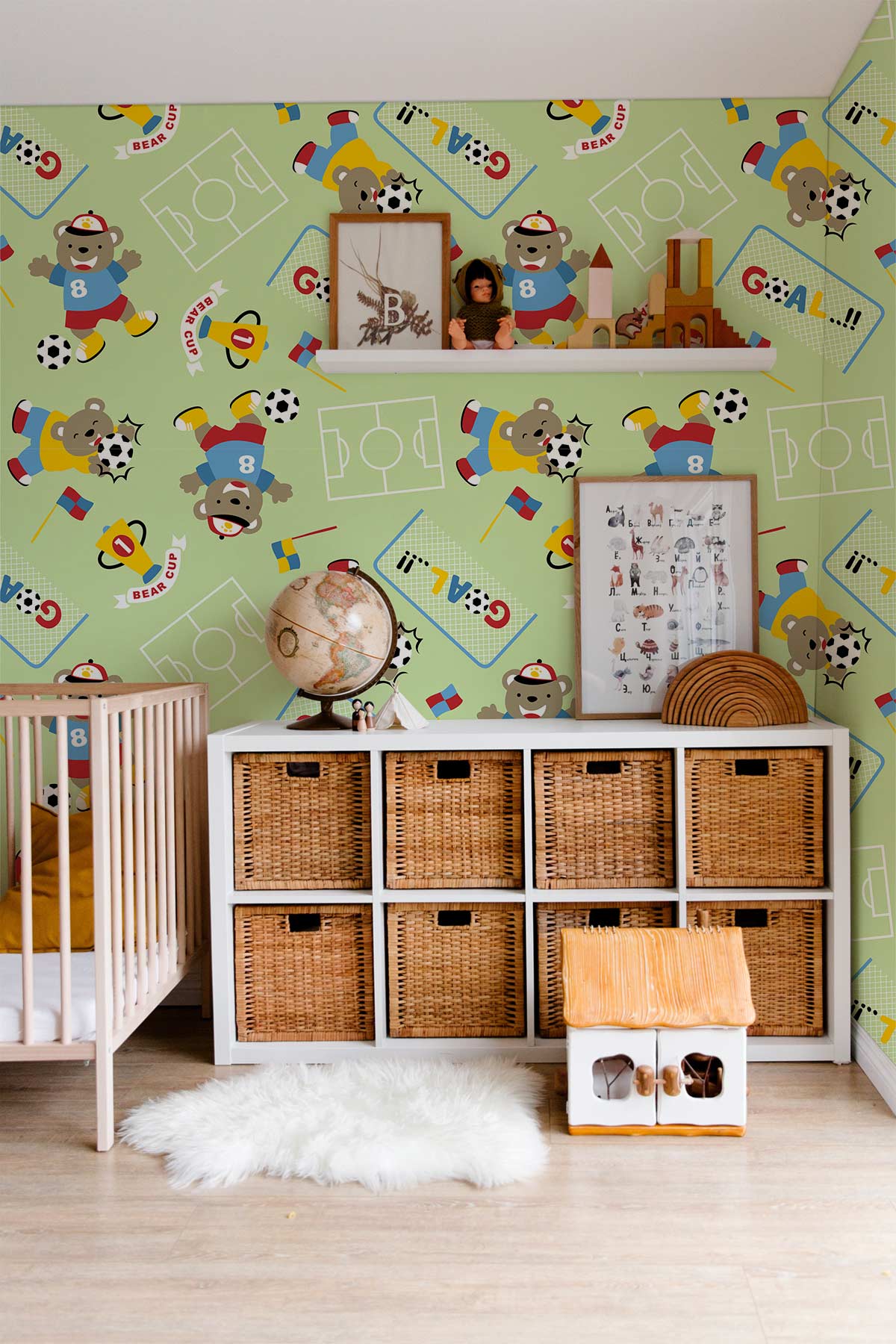 Playful Bear Football wallpaper with wicker storage unit, white cot, and rug in kids' room.