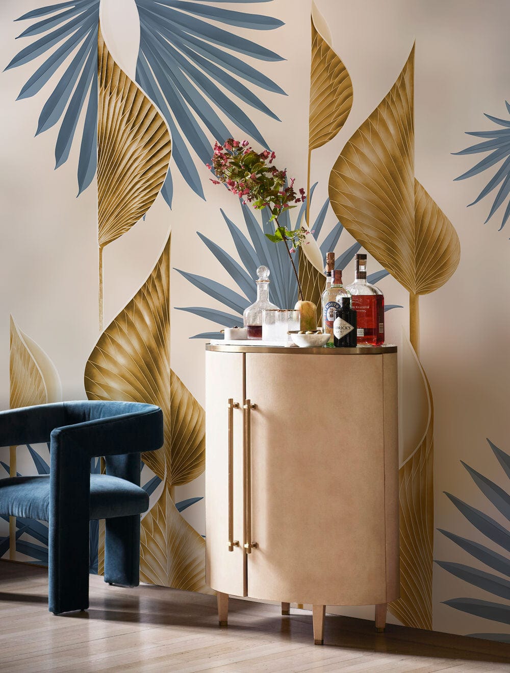 Elegant wallpaper with blue and gold botanical pattern, featuring a wooden cabinet and blue velvet chair.