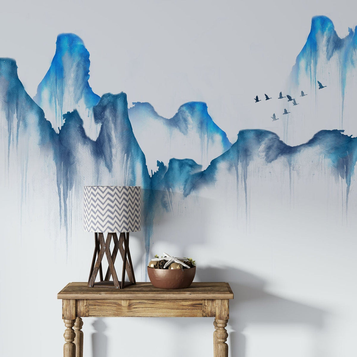Tranquil blue watercolour mountain mural; wooden table, chevron lamp, serene wall art, flying birds.