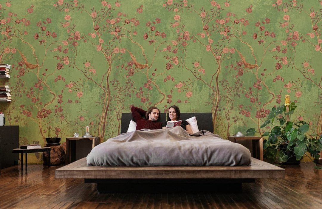 Vintage green floral mural wallpaper in bedroom with wooden bed, matching tables, and wooden flooring.