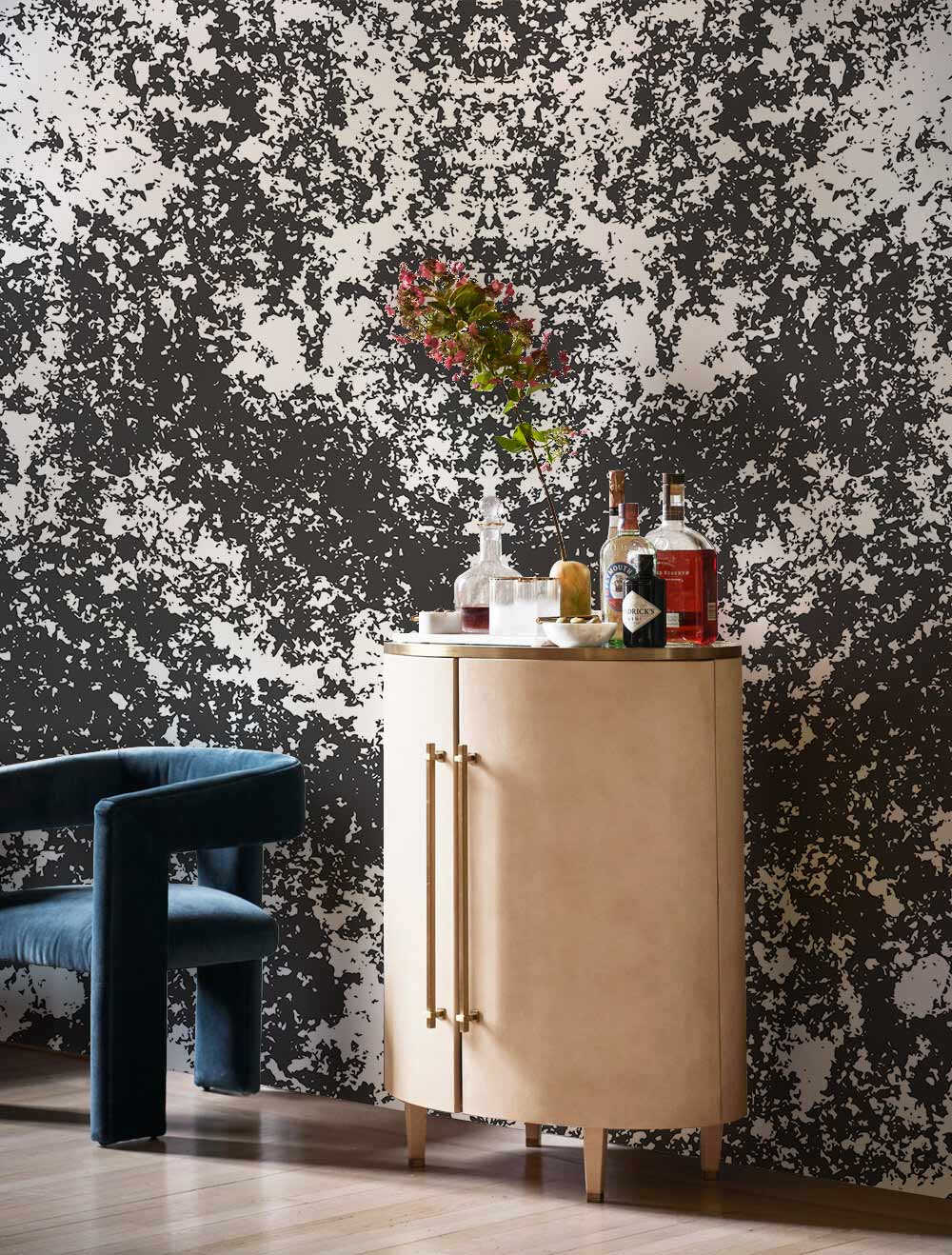 Monochrome abstract wallpaper in living room with elegant beige cabinet, blue velvet chair, wooden floor.