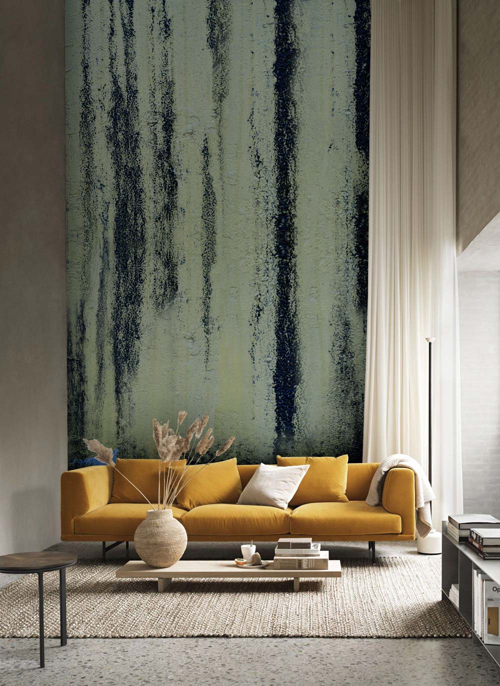 Rustic Charcoal Drip wallpaper enhances beige living room with mustard sofa, textured concrete flooring.