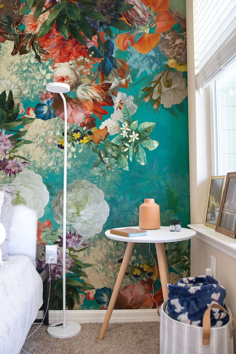Vibrant Floral Symphony mural wallpaper, teal floral design, shown in bedroom with white side table.