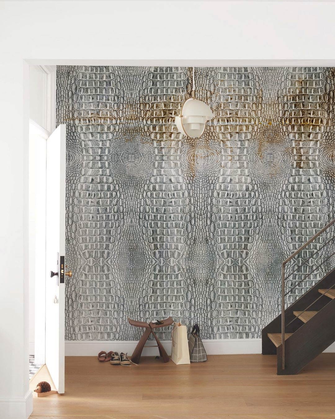Luxurious grey crocodile embossed wallpaper in modern hallway, wooden flooring, stylish staircase, chic decor.