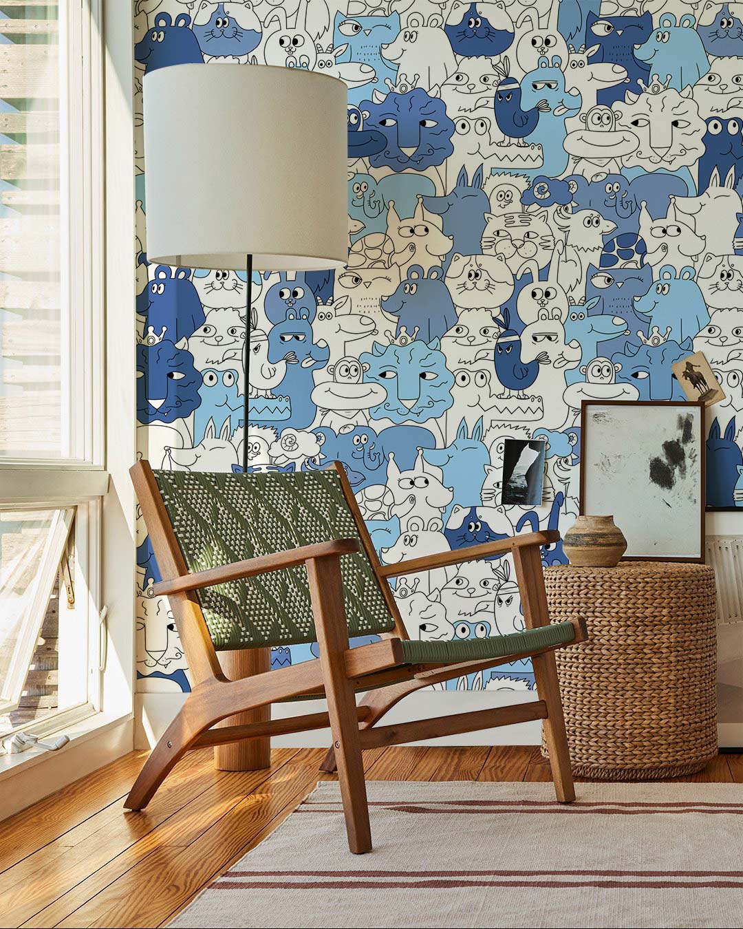 Playful cartoon animal wallpaper in blue and white with wooden chair, white lamp, wicker basket.