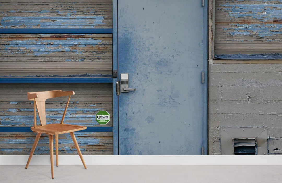 Vintage industrial wallpaper featuring blue weathered door with minimalist wooden chair in urban room.