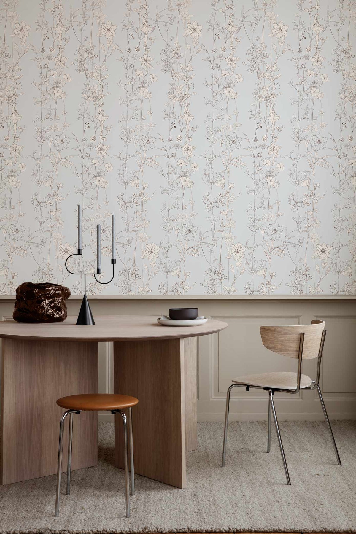 Elegant light blue floral wallpaper, wooden table, modern chairs, grey carpet, sophisticated room design.